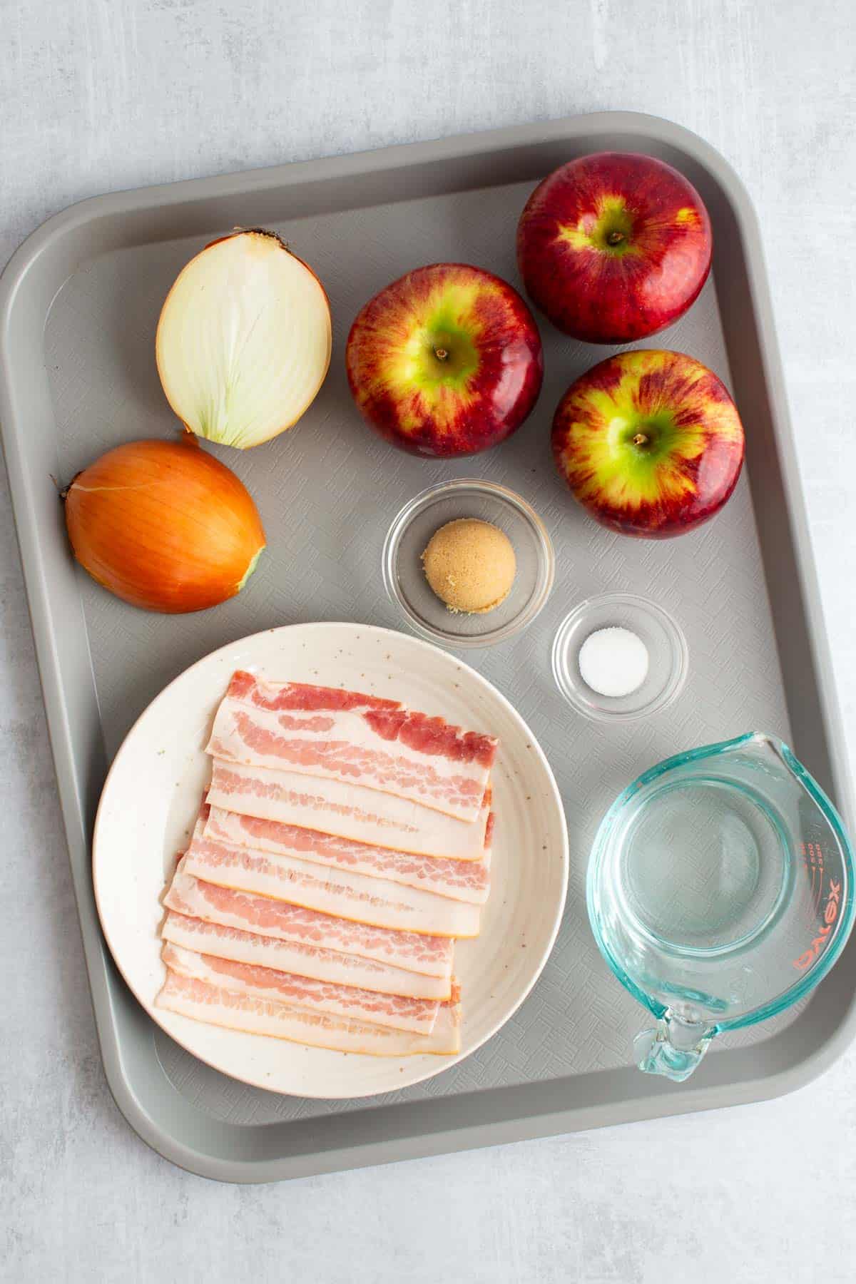 Ingredients for Apples and Onions, arranged on a sheet tray.