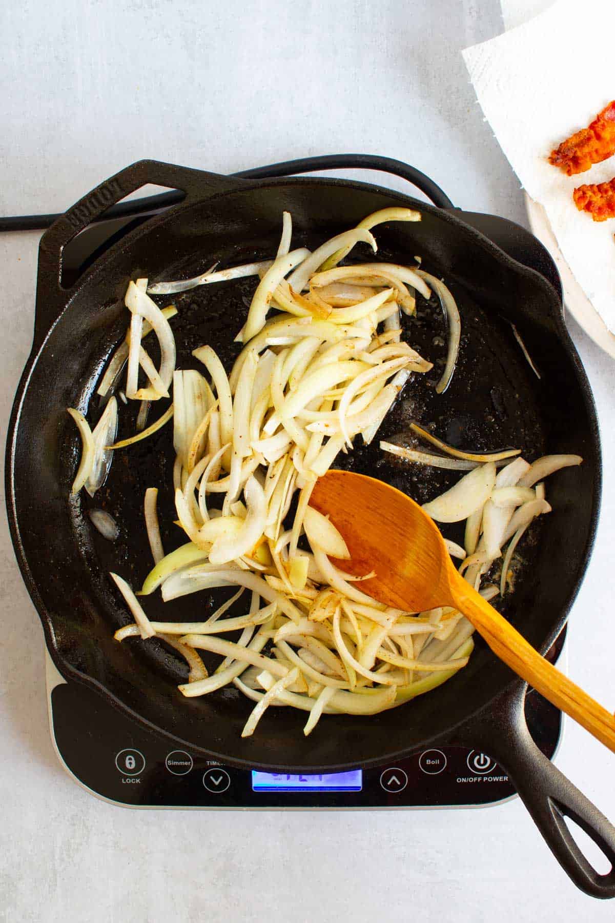 Sliced onions frying in bacon fat in a cast iron skillet for Apples and Onions.