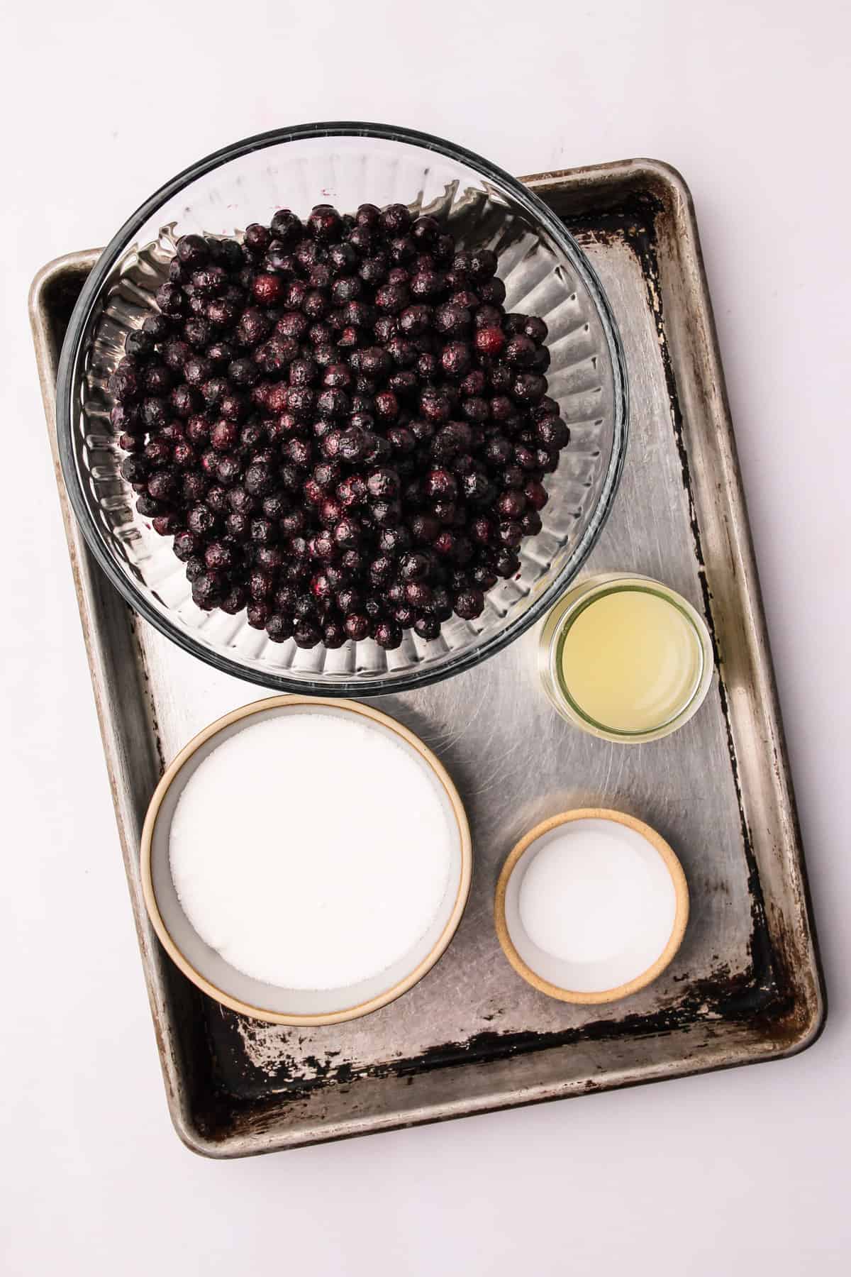 The ingredients for wild Maine blueberry jam measured into bowls on a baking sheet.