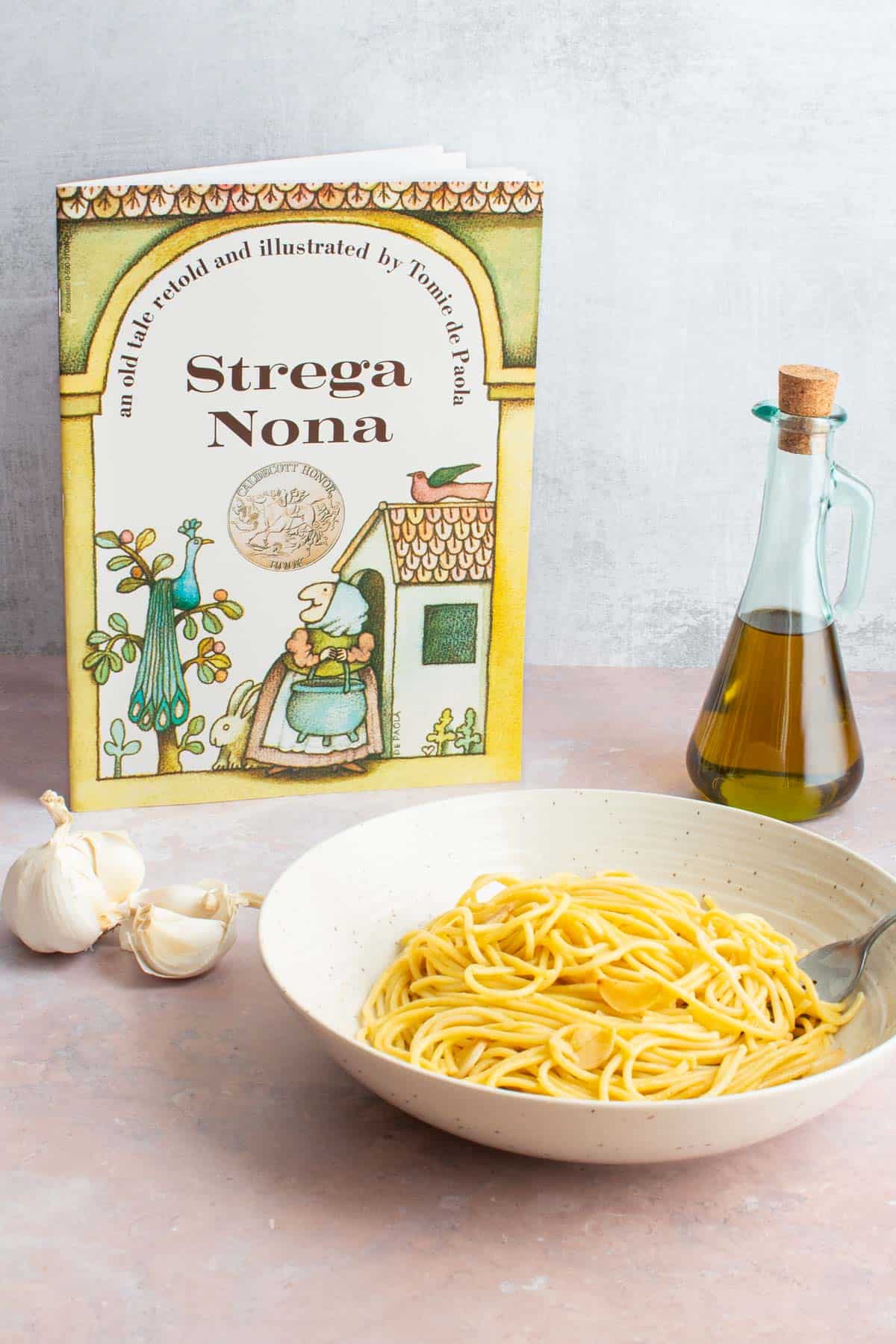 A bowl of Spaghetti and Garlic and Oil next to the book Strega Nona.