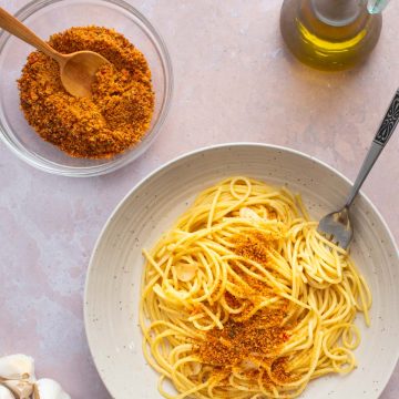 A bowl of Spaghetti and Garlic and Oil with spicy Calabrian breadcrumbs sprinkled on top.