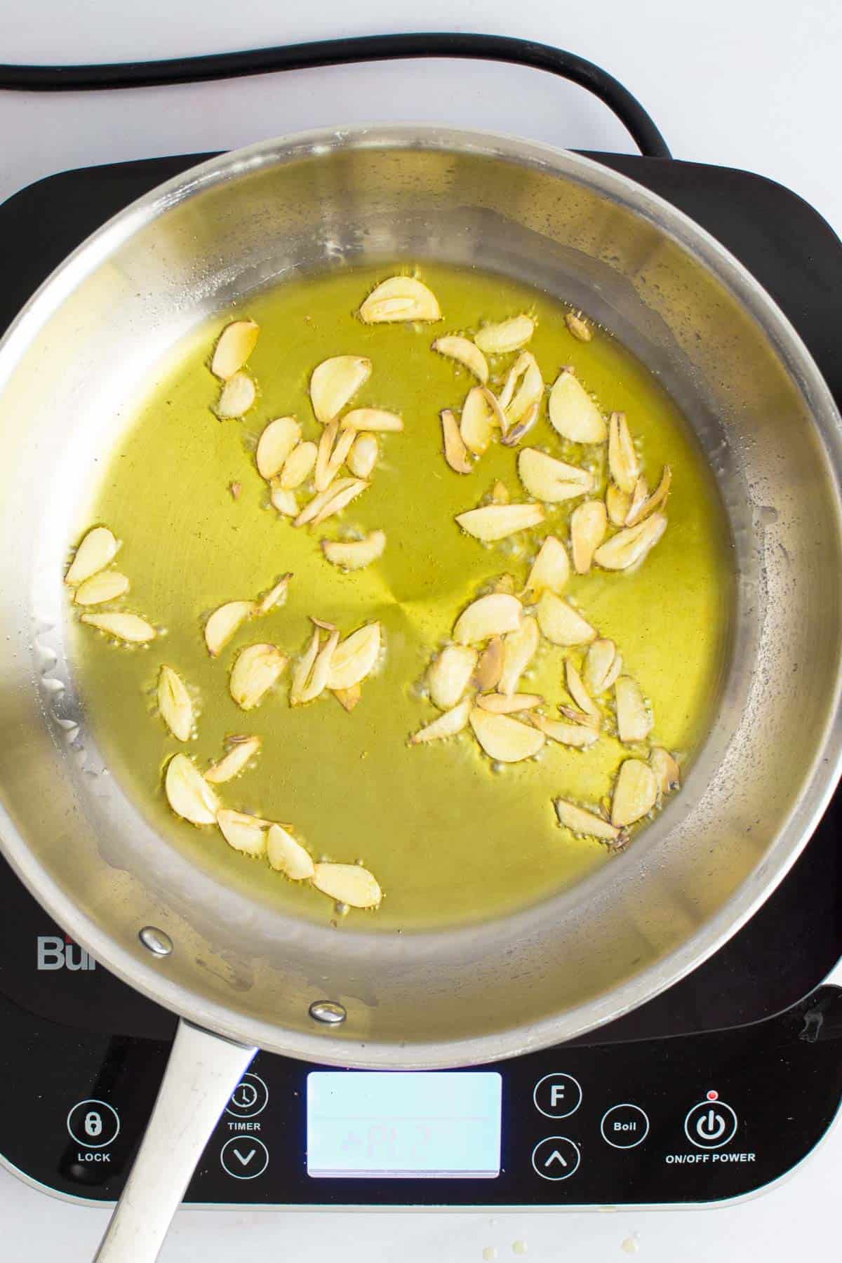 A skillet with oil and sliced garlic for Spaghetti with Garlic and Oil.