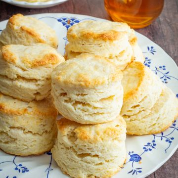 A plate of cream scones with homemade honey butter in the background.