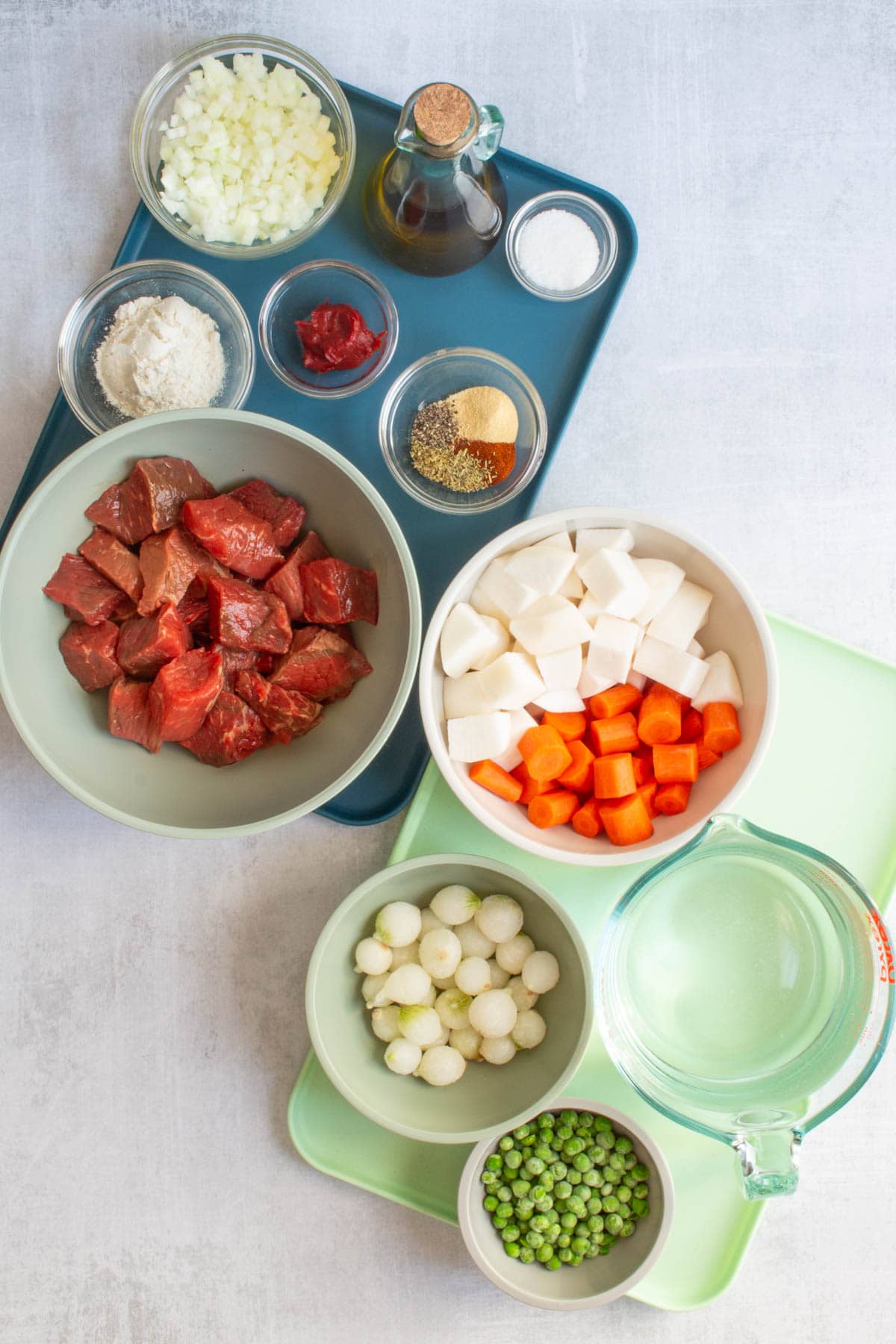 Two trays with bowls of the prepped ingredients for Dutch Oven Beef Stew.