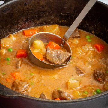 A pot and ladle filled with Dutch Oven Beef Stew.