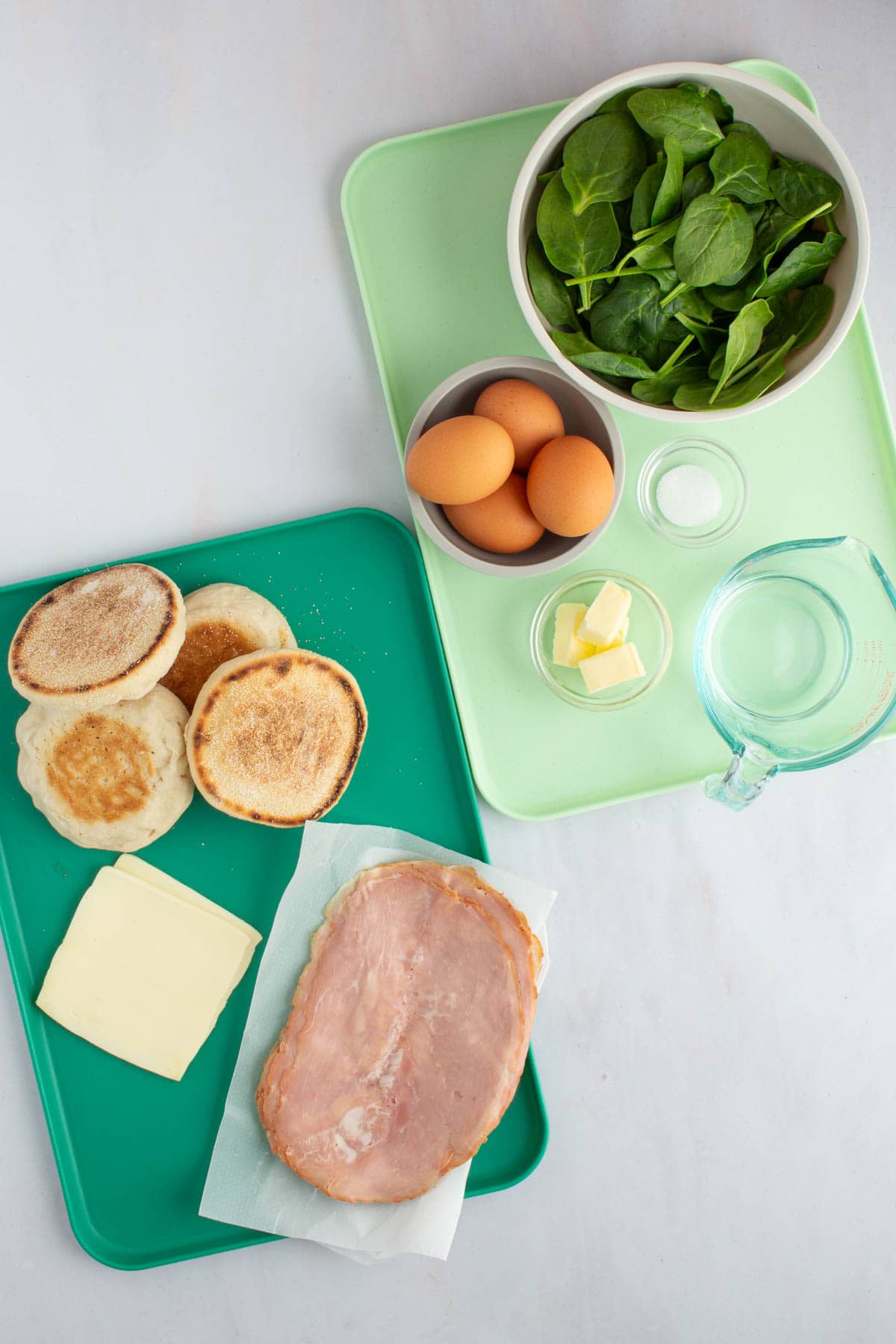 The ingredients for green eggs and ham breakfast sandwiches set out on two trays.