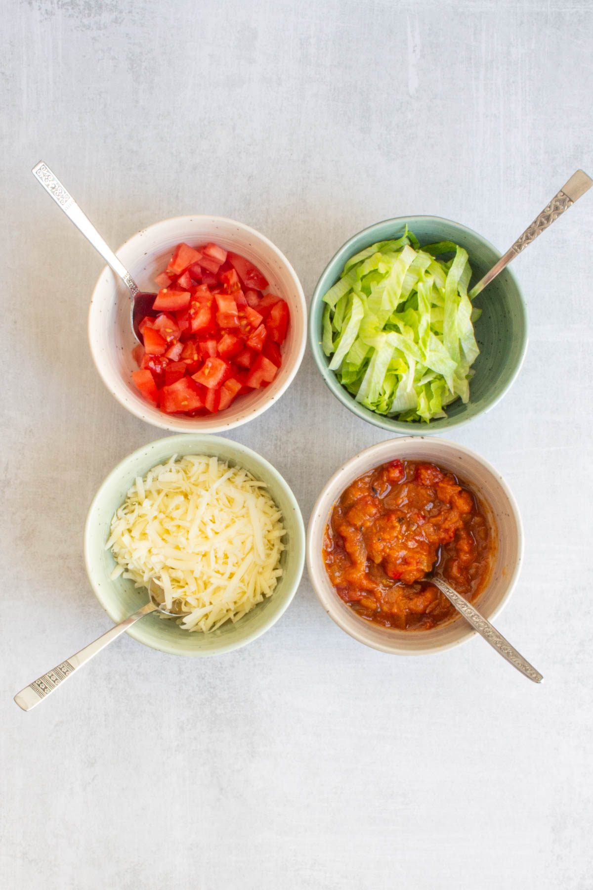 Toppings for Ground Beef Tacos in small bowls with spoons.