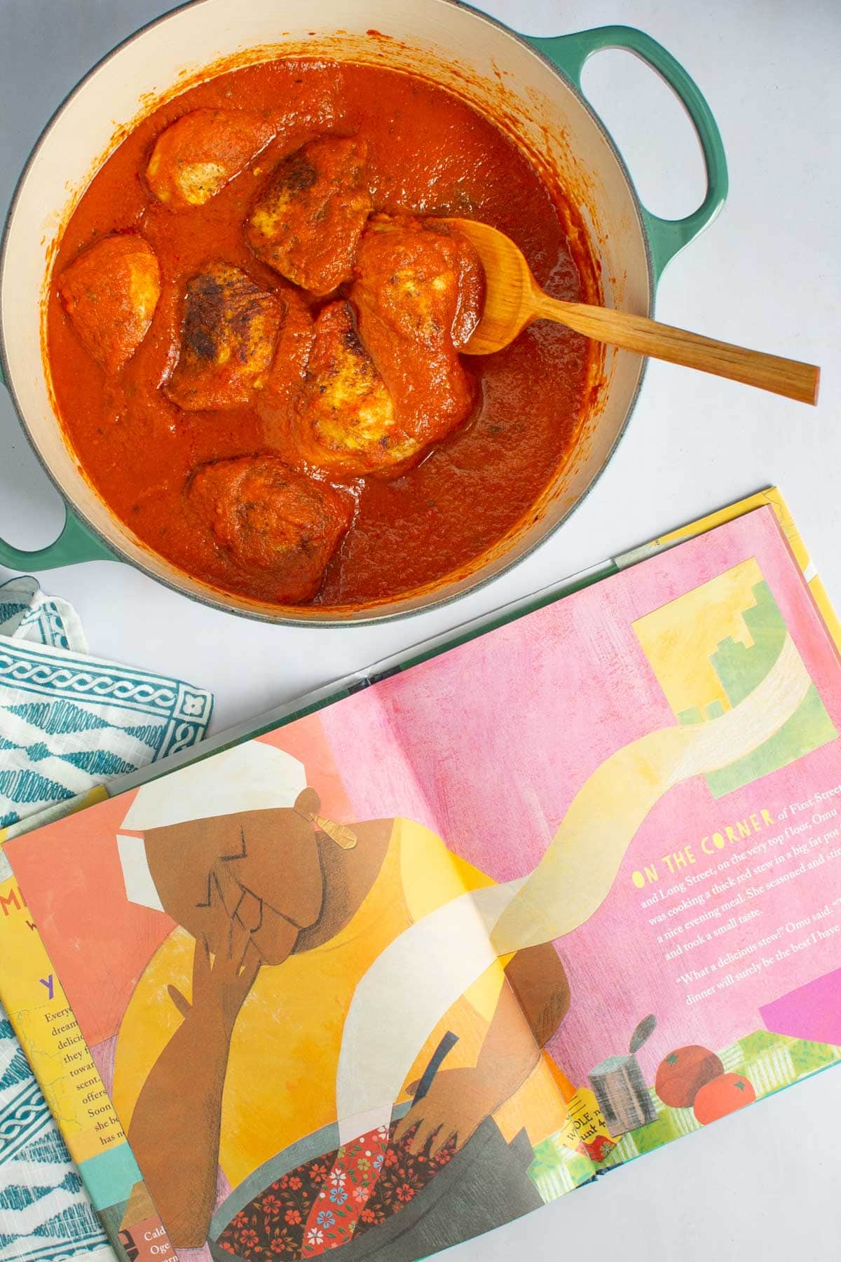 A pot of Nigerian Red Stew next to an open page of the book Thank You, Omu.