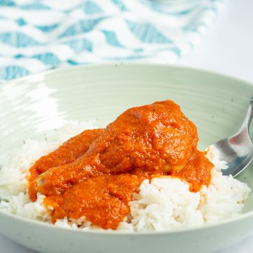 A serving bowl of Nigerian Red Stew over rice.