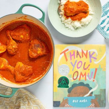 A pot and serving bowls of of Nigerian Red Stew with Chicken next to the cover of the book Thank You, Omu!