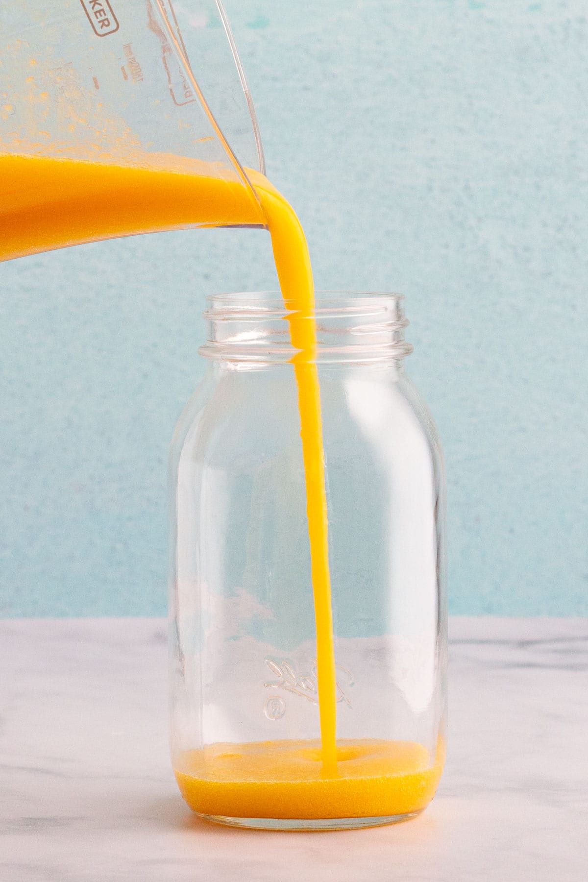 Spiced peach nectar being poured from a blender into a mason jar.