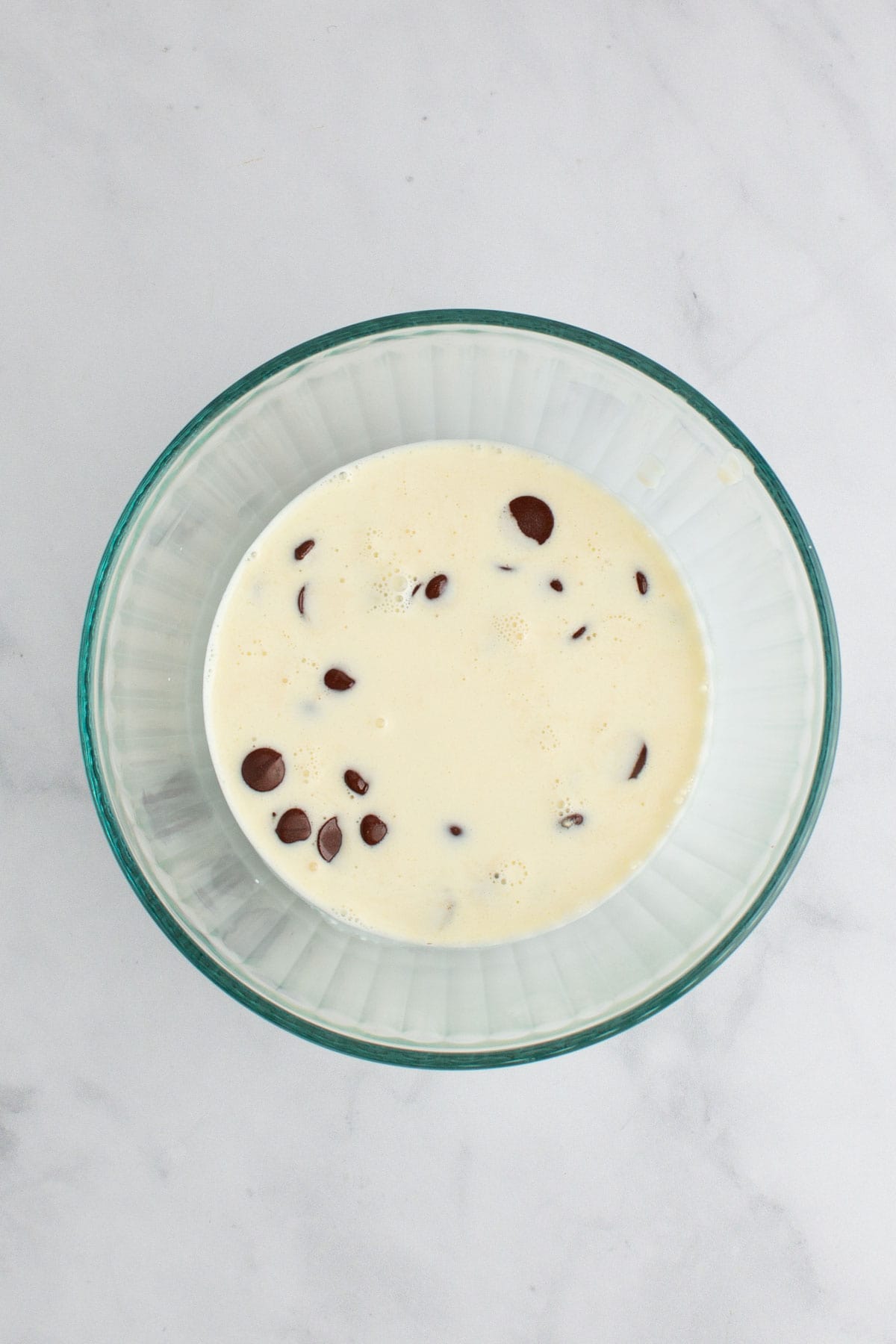 A bowl filled with heavy cream and chocolate chips for making ganache.