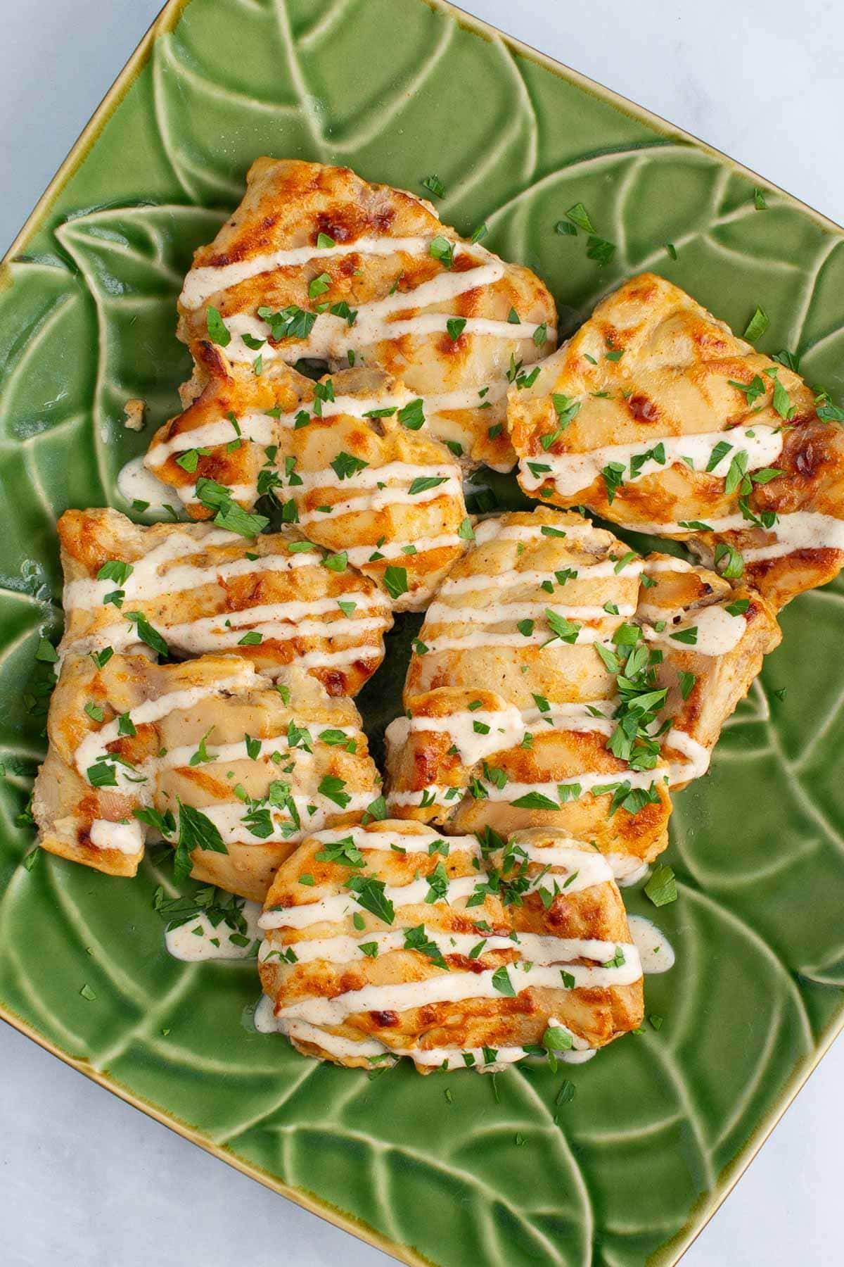 A platter of Juicy Yogurt-Baked Chicken sprinkled with parsley.