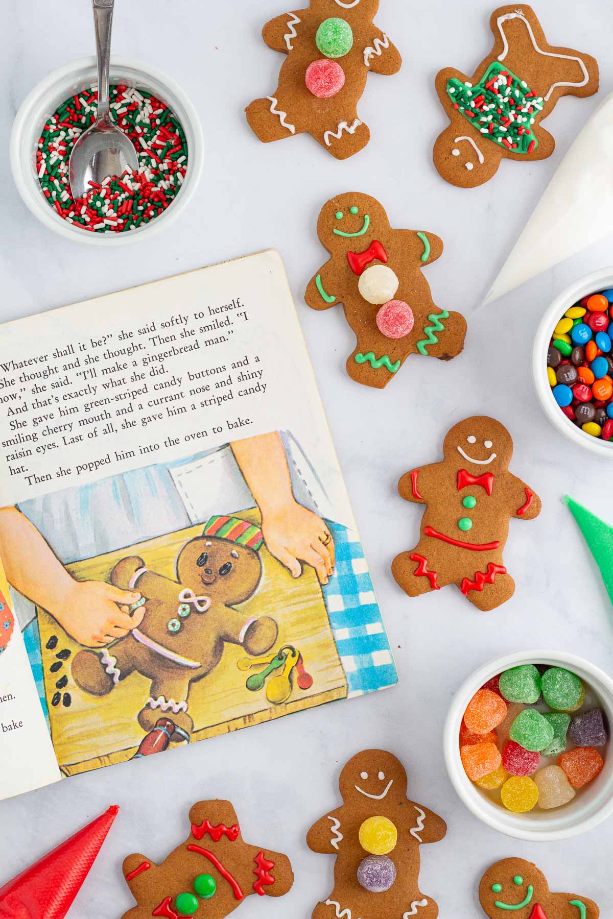 The book The Gingerbread Man open to a page, surrounded by baked gingerbread cookies and decorating supplies.