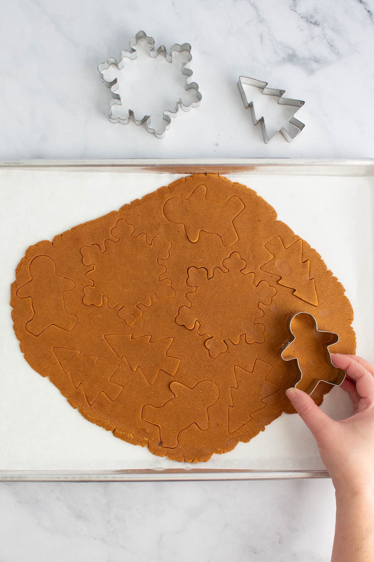 A hand using a cookie cutter to cut out easy gingerbread cookies.