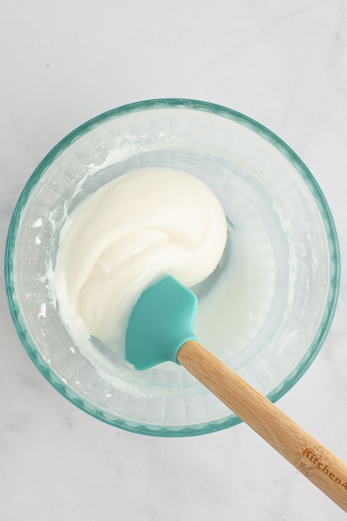 A spatula stirring together icing in a bowl for easy gingerbread cookies.