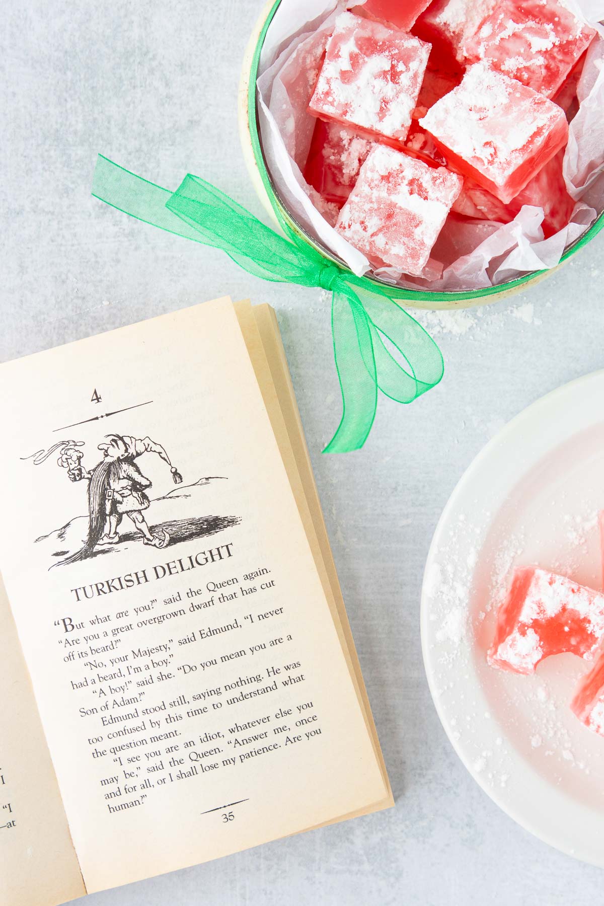 The book The Lion, the Witch, and the Wardrobe open to a page, next to a bowl and serving plate of Turkish Delight.