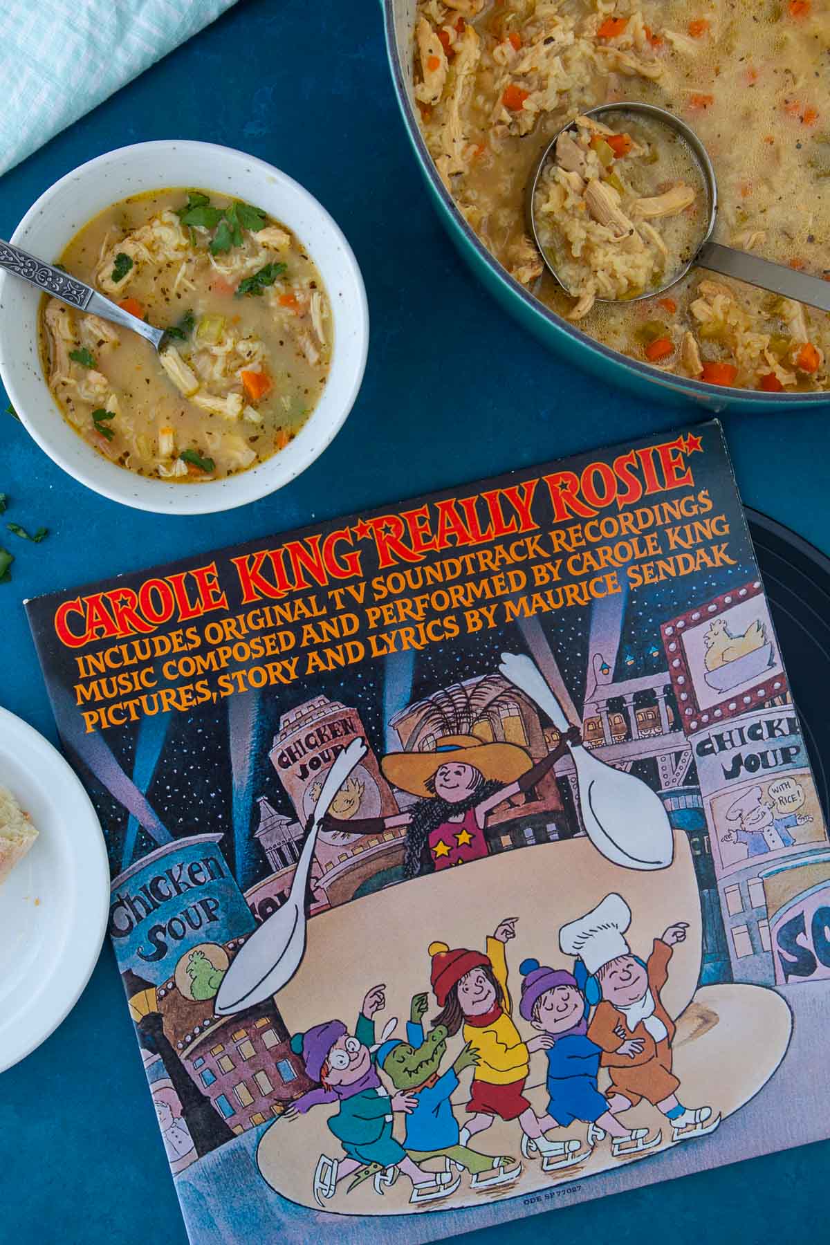 The cover of the record Really Rosie, next to a bowl and pot of chicken soup with rice.