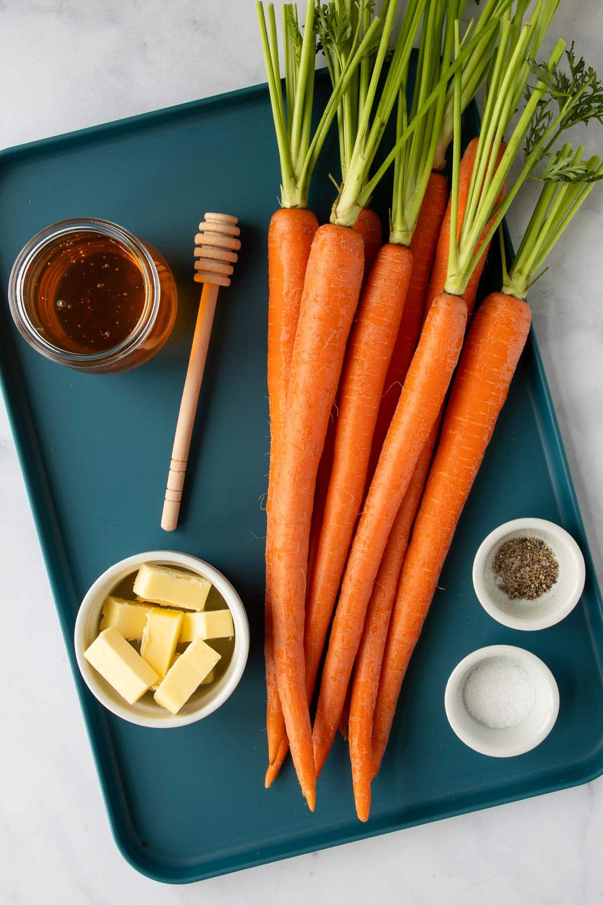 Ingredients for honey roasted carrots on a tray.