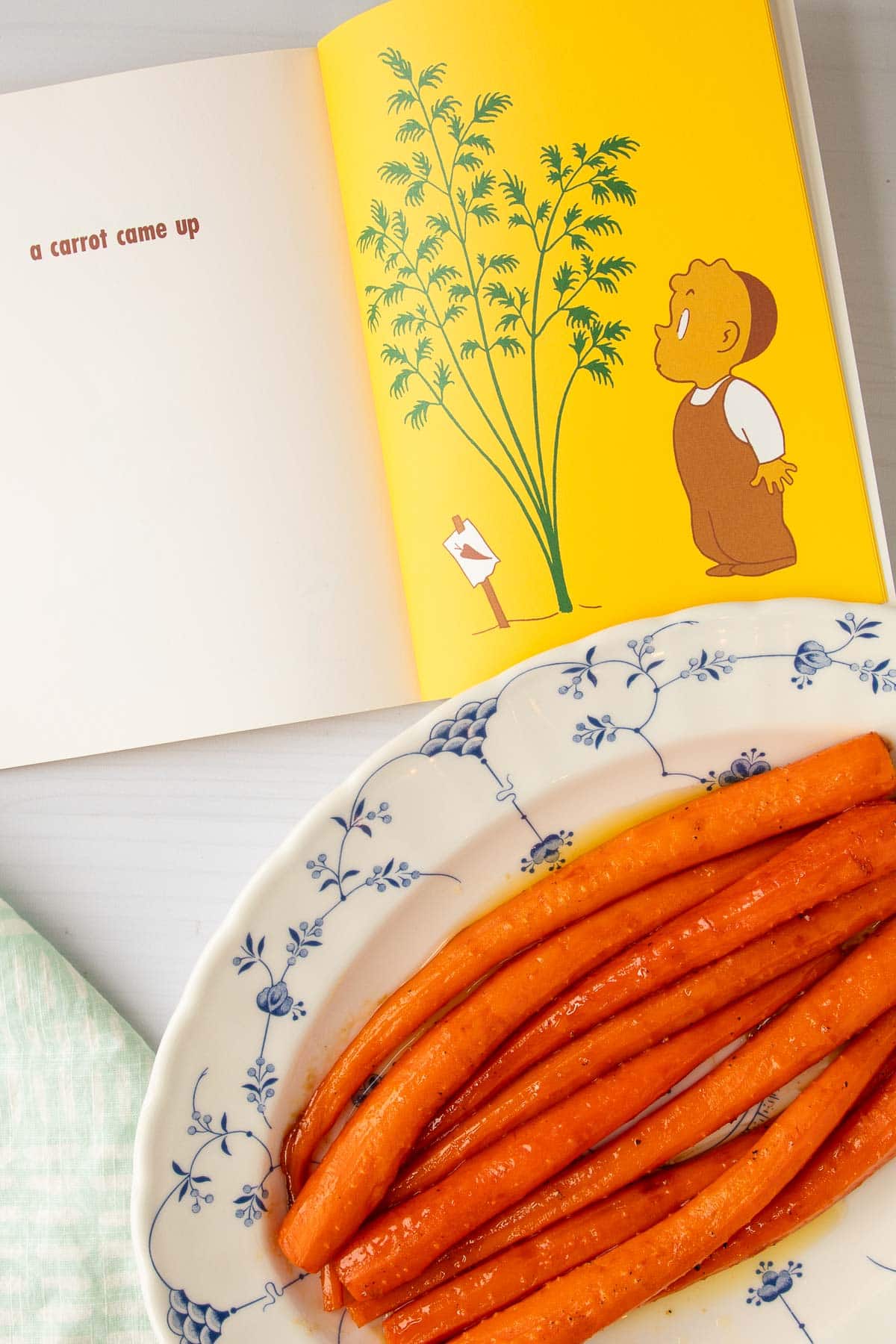 The book The Carrot Seed open to a page next to a platter of honey roasted carrots.