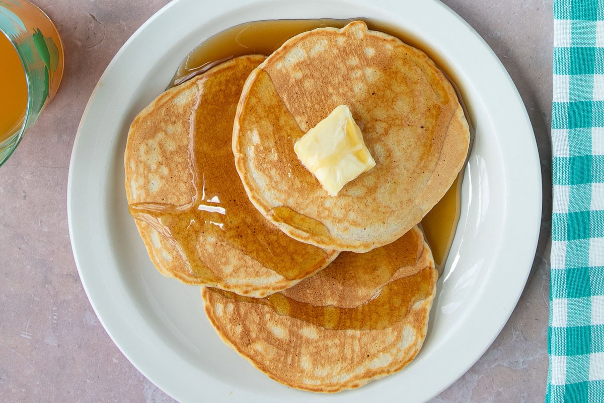 A plate of One-Bowl French Toast Pancakes, with syrup and butter on top.