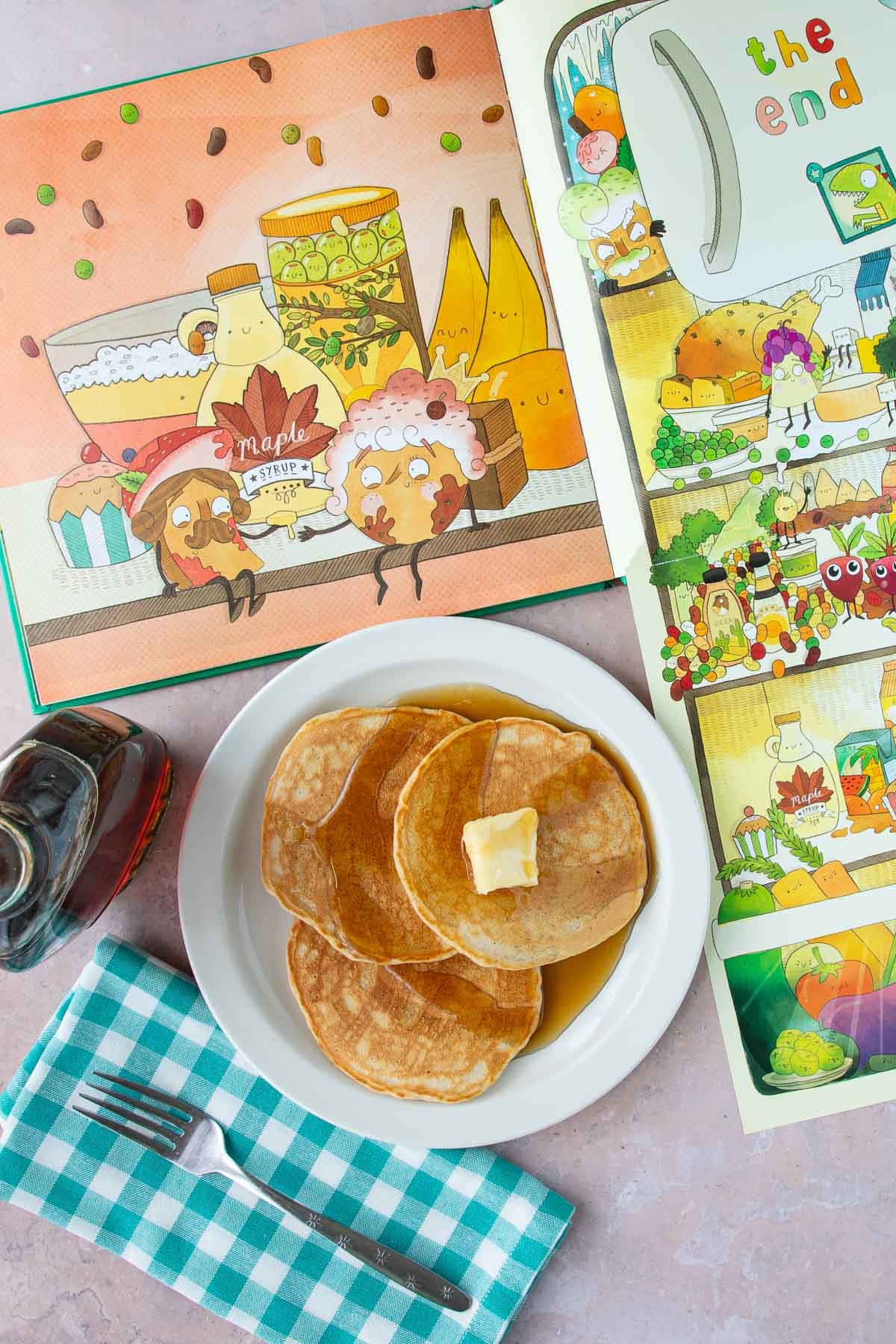 A plate of pancakes with syrup next to an open page from the book Lady Pancake & Sir French Toast.
