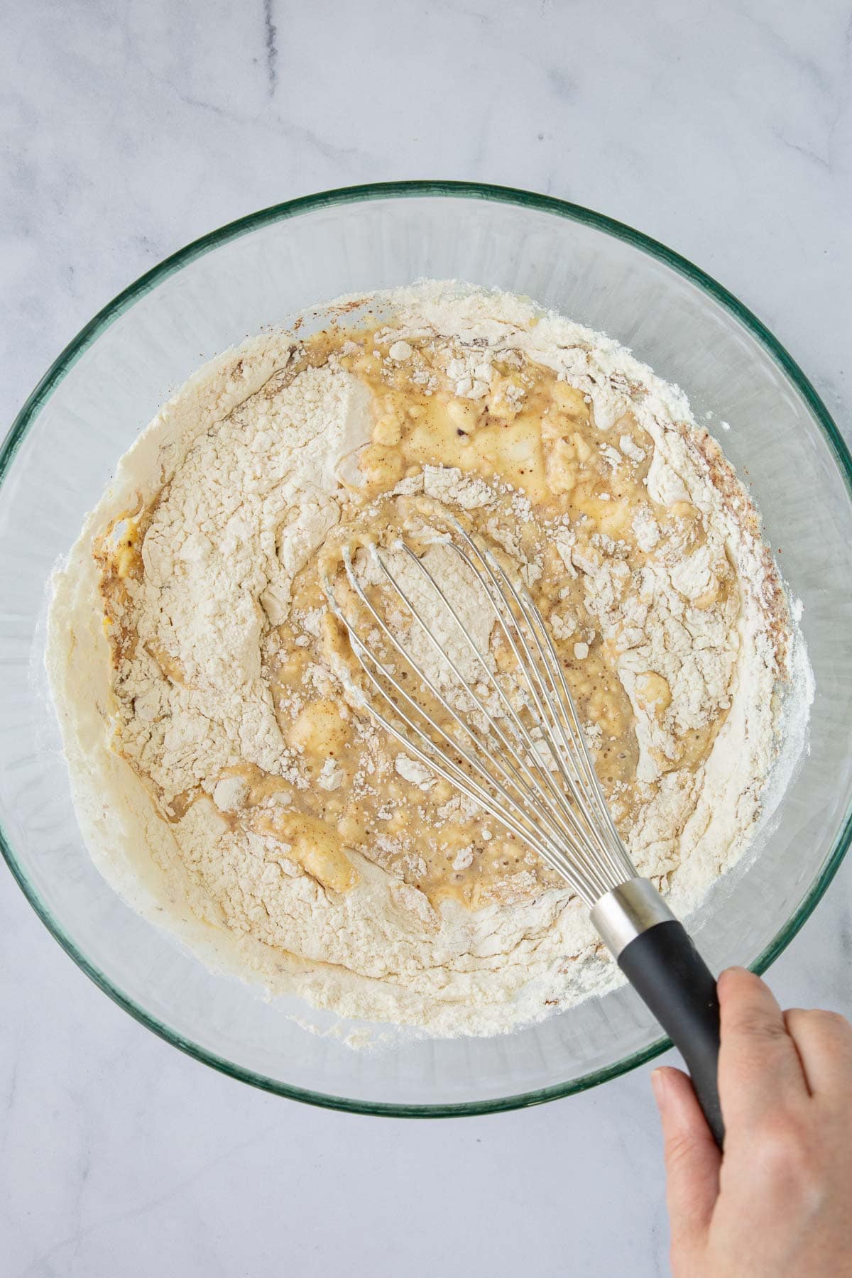 A hand whisking batter for One-Bowl French Toast Pancakes.