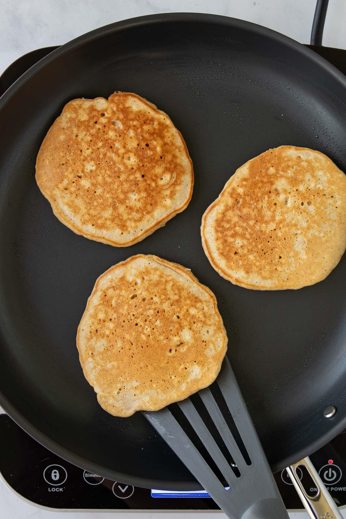 One-Bowl French Toast Pancakes cooking in a skillet.