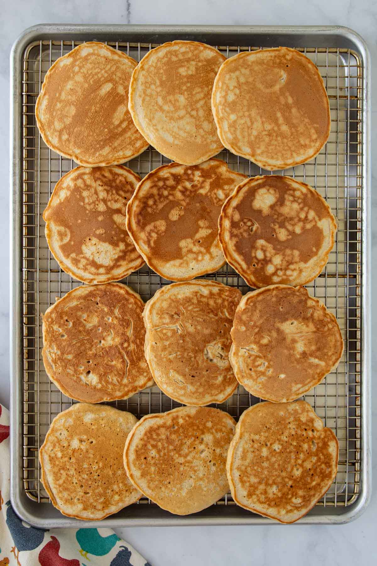 A dozen cooked French toast pancakes on a cooling rack.