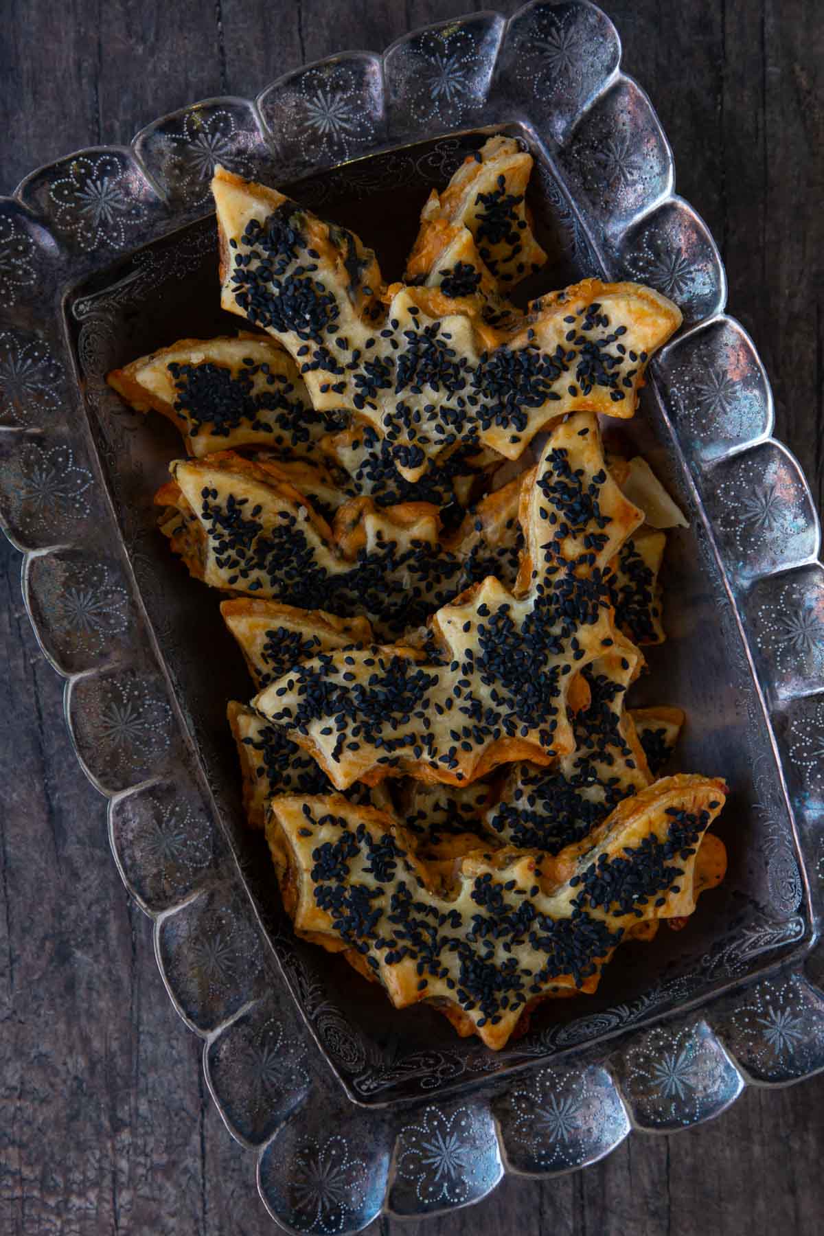 Baked cheddar-artichoke bat tarts in a silver serving tray.