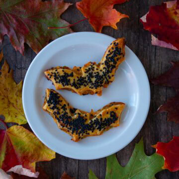 A plate of cheddar-artichoke bat tarts, surrounded by colorful fall leaves.